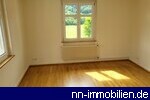 Helles Zimmer mit Parkettboden und groem Fenster mit Blick ins Grne