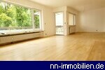 Heller, grozgiger Wohnraum mit groen Fenstern und hellem Holzboden, der noch abgeschliffen wird.